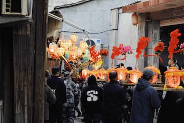 人群抬着灯笼和装饰品在街道上行进庆祝活动气氛浓厚