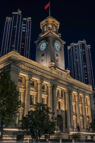 夜幕下的外滩建筑群灯光照亮古典建筑与现代高楼红色旗帜在顶端飘扬