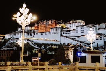 夜幕下的布达拉宫被灯光照亮，展现出其宏伟的建筑结构。