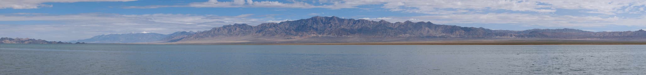 广阔水面映衬远山山脉连绵起伏天空云朵点缀景色壮丽