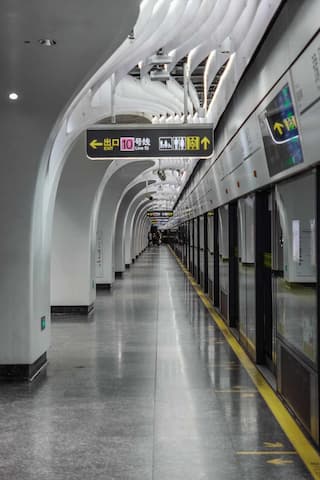 空旷的地铁站台设计现代 站台地面光亮 顶部的装饰独特 列车停靠在站台旁