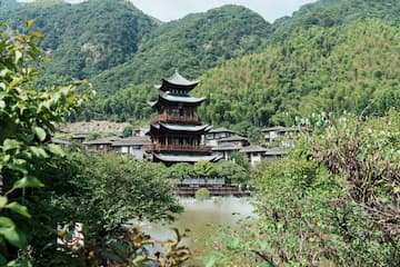 图片展示了一座位于山间的古塔，周围环绕着绿树和村落。