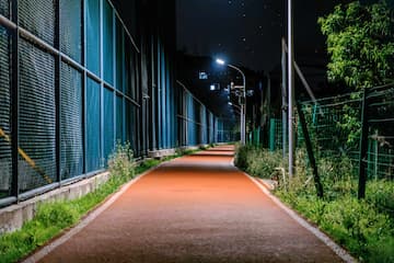 夜晚的跑道被灯光照亮 跑道两旁有围栏和植物