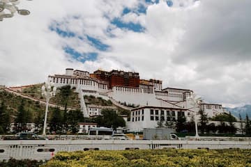 图片展示了位于山顶的布达拉宫，天空中有云朵。