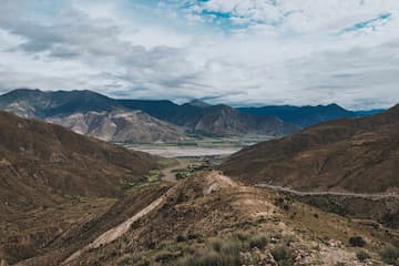 图片展示了山谷中的自然景观，包括山脉、河流和天空中的云层。
