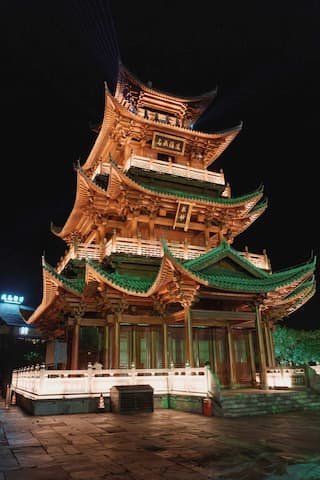 图片展示了一座在夜间被灯光照亮的中国传统多层塔楼建筑。