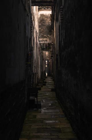 狭窄的巷道两旁是高耸的墙壁砖石铺就的路面延伸至远方光线昏暗