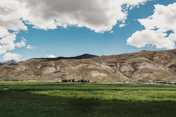 图片展示了绿色的草地，远处的山丘以及蓝天白云。