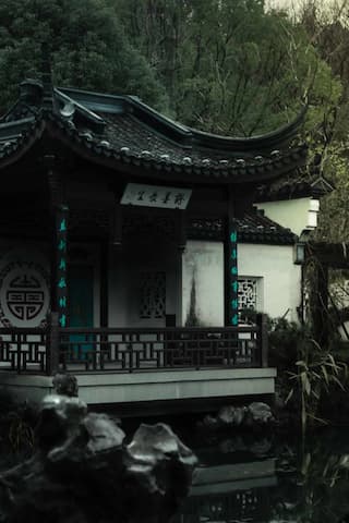 The image shows a traditional Chinese building next to water surrounded by trees.
