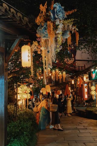 夜色下的古镇，挂满了灯笼，一些游客在街上行走。