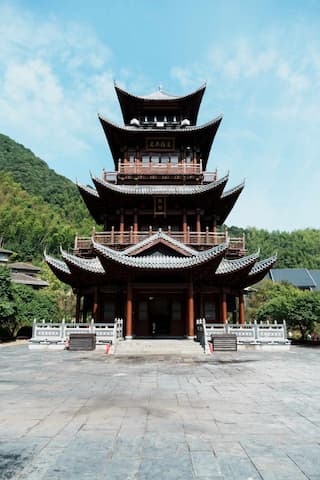 图片展示了一座多层中国传统宝塔建筑，具有飞檐设计，周围环绕着绿树青山。