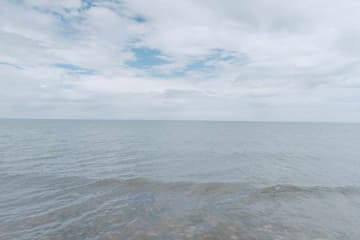 平静的海面延伸至地平线 天空布满云朵 只有少量蓝色天空可见