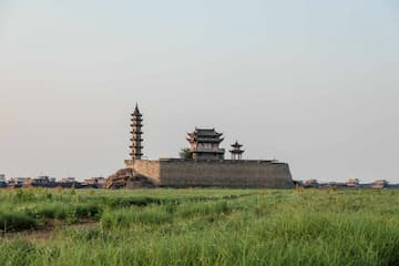 图片展示了古老的城墙建筑 搭配着绿色的草地 营造出一种历史与自然和谐共生的氛围