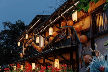 图片展示了夜晚的古建筑，建筑上挂满了灯笼，红色花朵作为点缀。