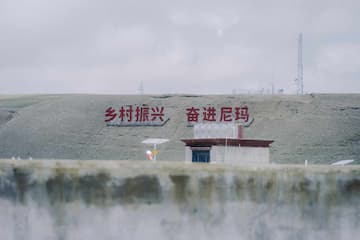 图片展示了写有“乡村振兴 奋进尼玛”标语的草地和建筑