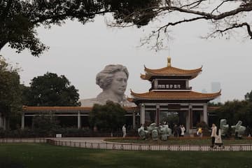 江阁建筑风格独特 雕像人物面部轮廓清晰 绿地树木环绕