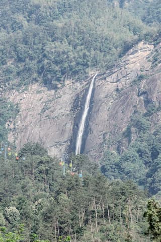 山崖上飞流直下的瀑布山间绿树葱茏还有缆车穿梭其中