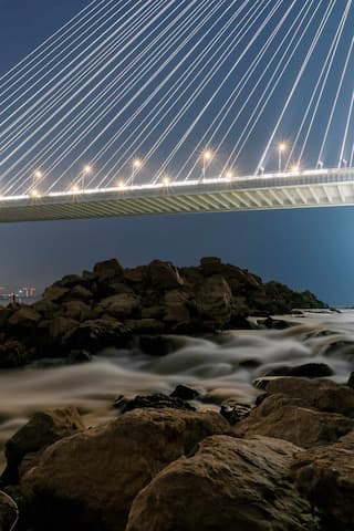 夜景拍摄桥梁底部水流经过岩石表面桥上灯光点亮天空