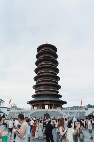 一座多层塔楼矗立在广场上，周围聚集着许多游客。