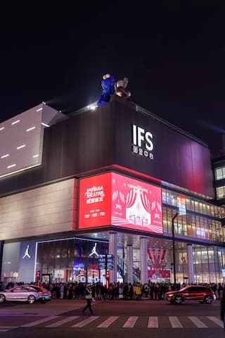 夜幕下的IFS建筑灯火辉煌 楼顶的雕塑引人注目 楼下人潮涌动车辆穿梭