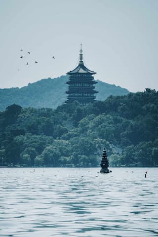 湖面上可见小塔远山上有高塔飞鸟掠过水面波光粼粼