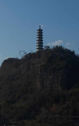 图片展示了一座山顶上的宝塔 在蓝天的映衬下显得格外醒目 山上植被茂盛