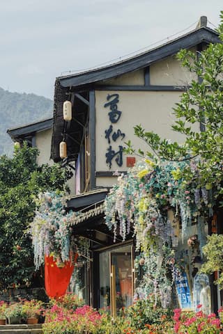 图片展示了一栋传统风格的建筑，建筑外墙上装饰着鲜花和绿植，悬挂着灯笼。