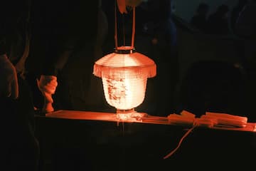 昏暗光线下 灯笼发出柔和的光芒 旁边有雕像和纸张
