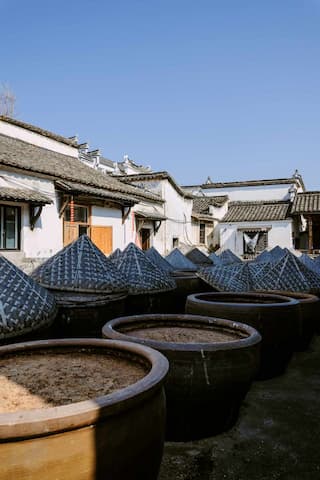 许多大酱缸排列在徽派建筑前 酱缸部分盖着锥形盖子