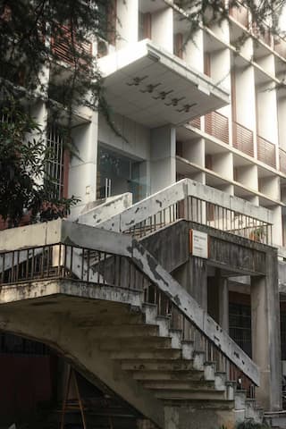 图片展示了一栋建筑的外立面 建筑风格独特 搭配水泥楼梯 整体呈现出一种简约的风格