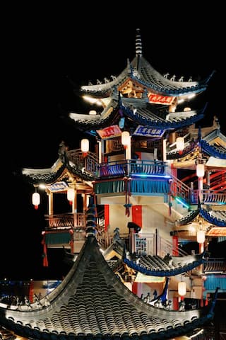 夜色中一座多层的中国传统风格建筑，装饰有灯笼和彩灯。