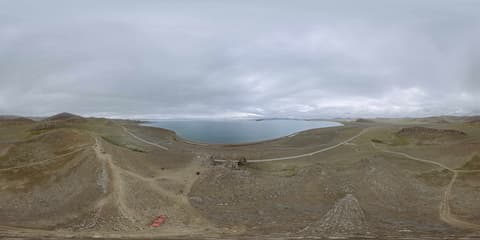 全景照片展示了湖泊周围的荒凉地貌，天空阴沉。