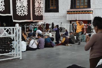 一群人在寺庙前的空地上或站或坐。