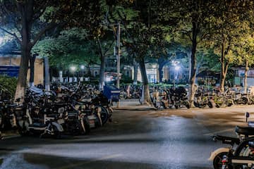 夜晚的停车场停满了自行车和电动车 灯光照亮地面 树木在周围
