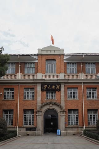 这是一栋红砖建筑，可能是南开大学的主楼，顶部飘扬着旗帜，建筑风格庄重
