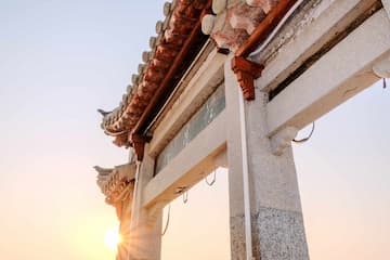 白色石质牌坊在日出光辉中呈现古朴之美 建筑细节精致 屋檐线条流畅