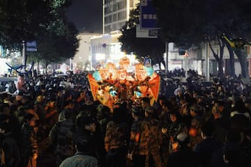 夜间街道上人群聚集观看表演或活动 远处有灯光照亮的建筑物