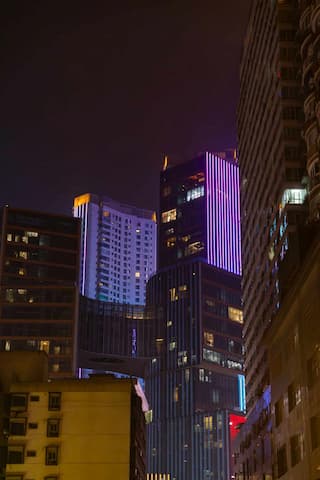 夜幕下的城市高楼建筑群灯光点缀紫光灯带醒目街道视角仰望高楼