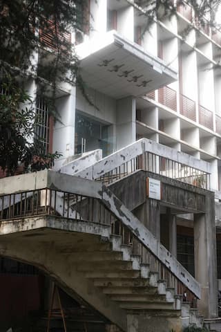 建筑外立面有水泥楼梯和白色外墙 楼梯有些老旧 建筑风格较为朴素