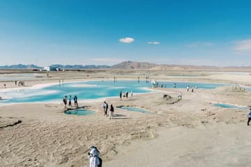 一群人在盐湖边行走 湖水呈现出美丽的蓝色 天空晴朗