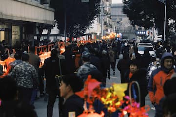 街道上聚集了大量人群 远处有灯笼和车辆