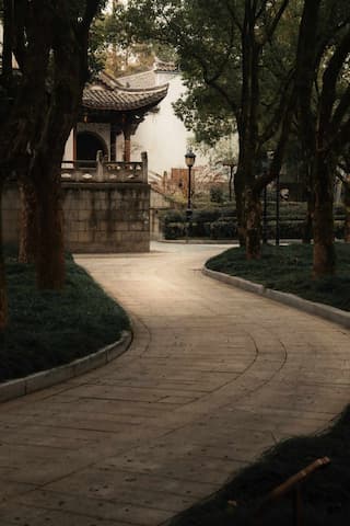 蜿蜒小路通向庭院建筑树木环绕光线柔和营造宁静氛围
