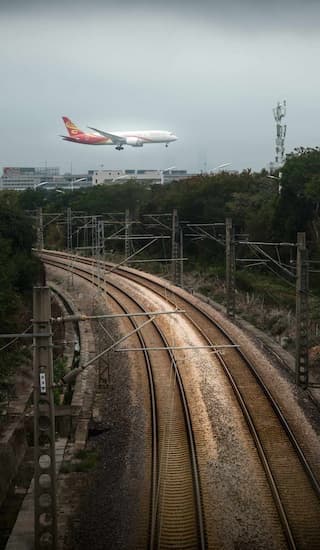 飞机低空飞行准备降落下方是弯曲的铁轨和树木