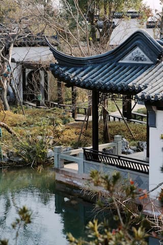 图片展示了中式园林建筑 飞檐翘角 临水而建 周围绿植环绕 水面平静