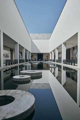 白色建筑围绕水池 水面反射建筑结构 圆形石块漂浮水面之上