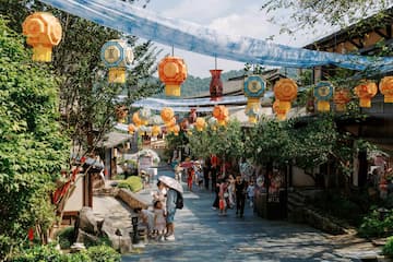 图片展示了一个挂满灯笼的古镇街道，有游客在其中行走。
