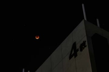 夜空中一轮血月悬挂在建筑物上方