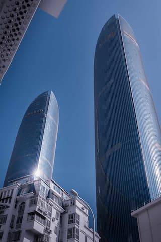 仰视视角拍摄两座高耸的现代摩天大楼 建筑外观呈流线型 玻璃幕墙反射天空光芒