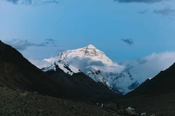 图片展示了被云雾环绕的雪山山顶，山谷深邃，天空湛蓝。