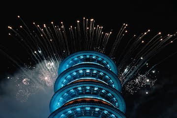 蓝色塔状建筑在夜空中被烟花照亮。